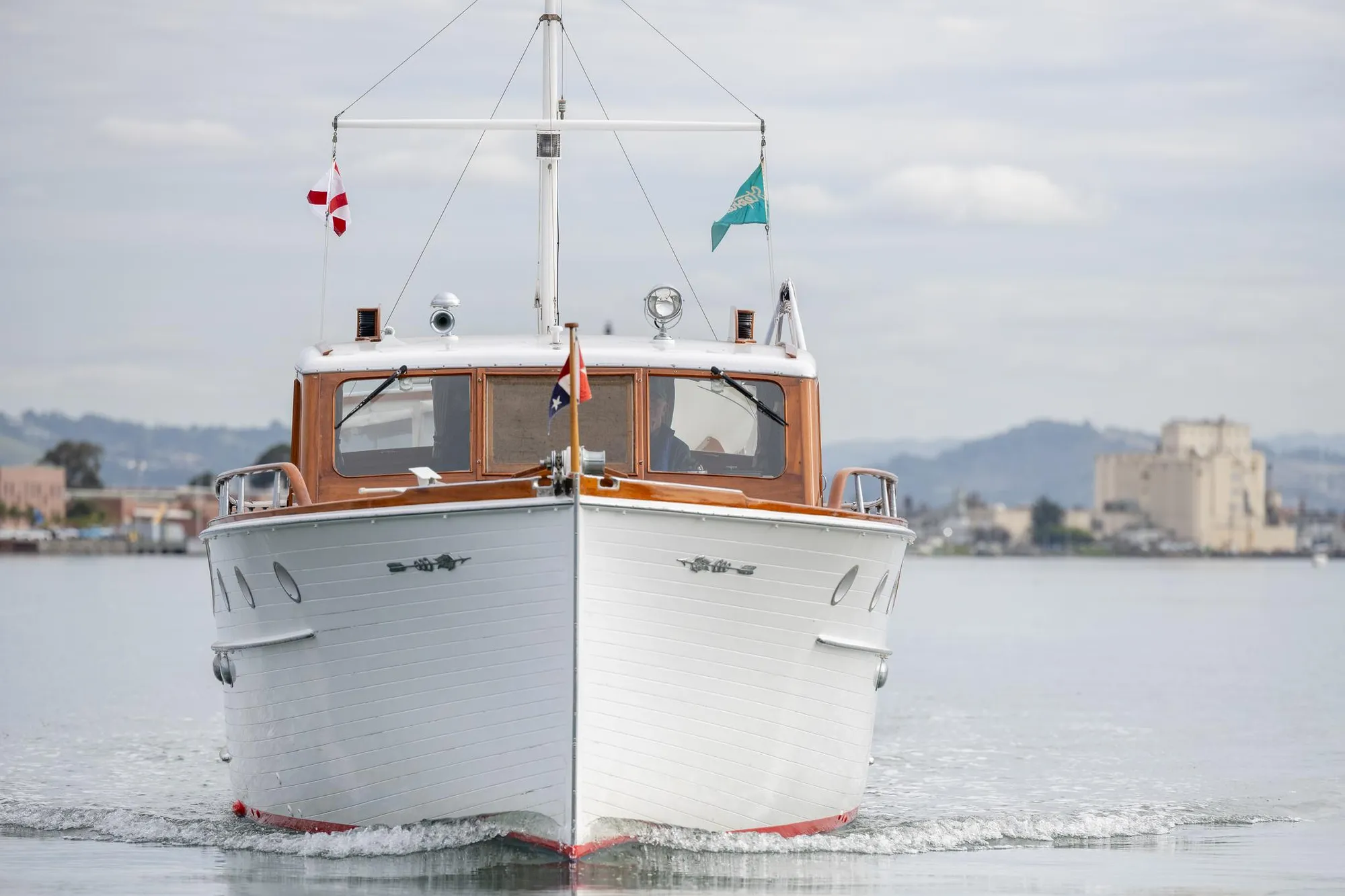 1939 Stephens Brothers Bridgedeck Cruiser on calm water, front view, with cityscape background.