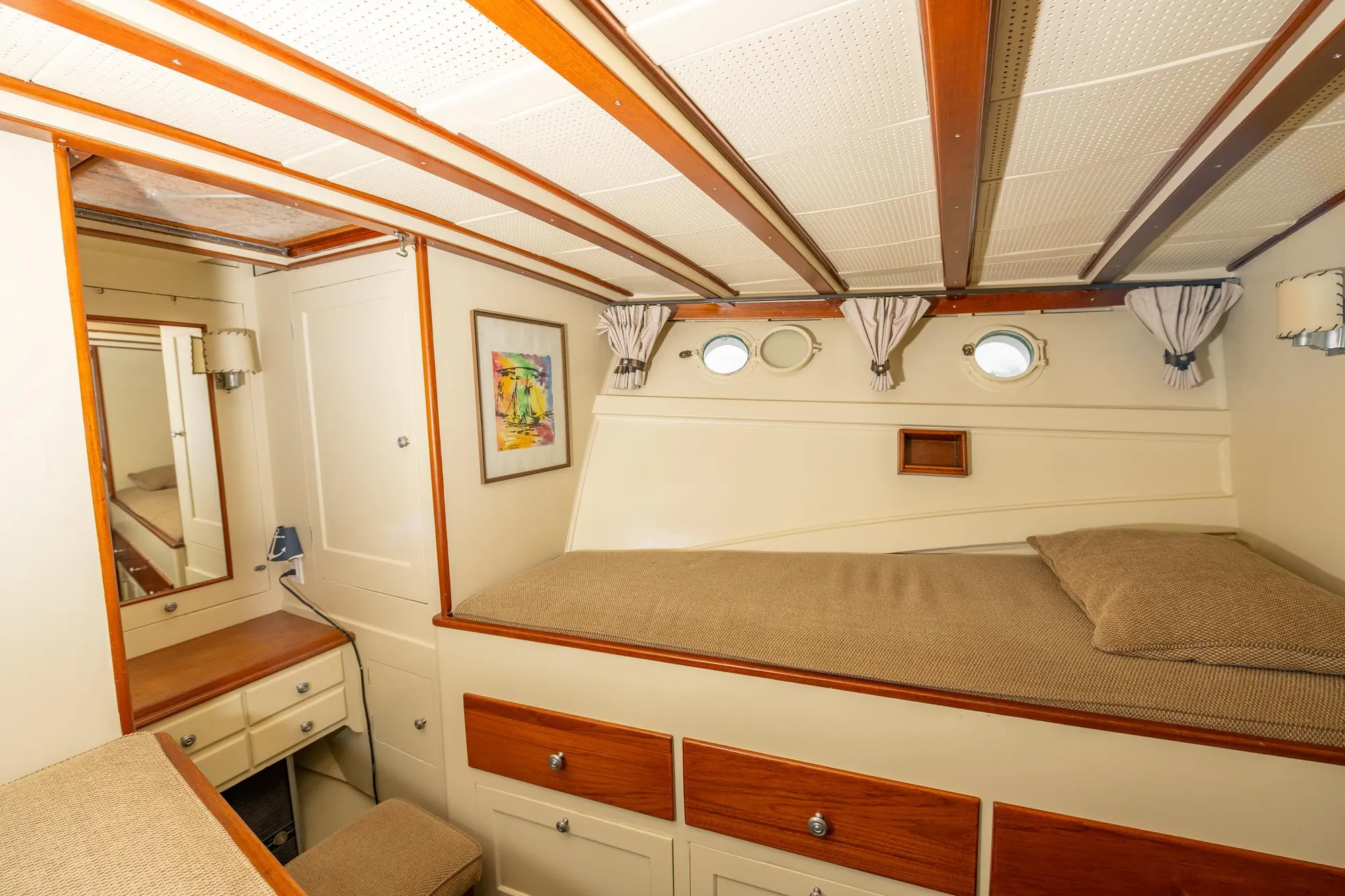 1939 Stephens Brothers Bridgedeck Cruiser cabin interior with bed, portholes, and wooden accents.