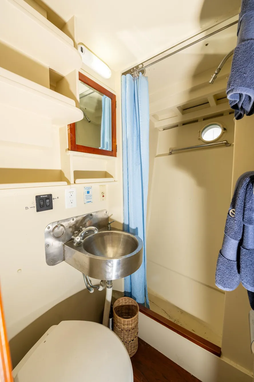 1939 Stephens Brothers Bridgedeck Cruiser bathroom with sink, shower, and blue towels.