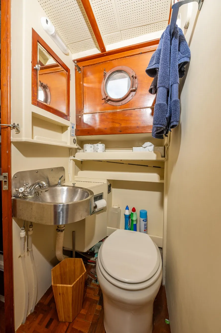 1939 Stephens Brothers Bridgedeck Cruiser bathroom with porthole, sink, and toilet.