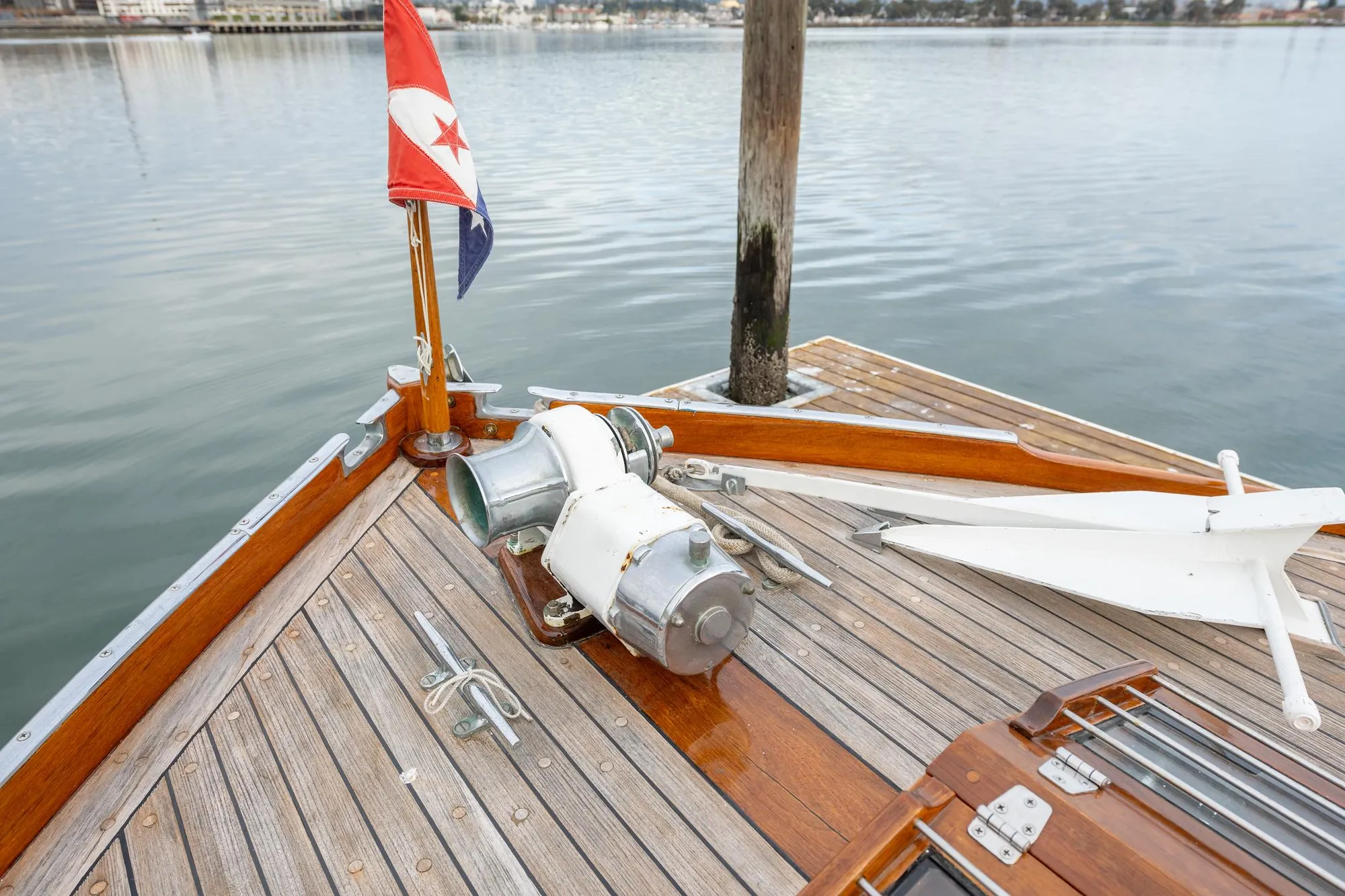 1939 Stephens Brothers Bridgedeck Cruiser bow with anchor and flag on wooden deck.