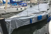 Covered 1977 Custom Scalar 28 sailboat docked in marina with blue fenders.
