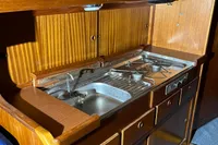 1977 Custom Scalar 28 boat kitchen with wooden cabinetry and compact stove.