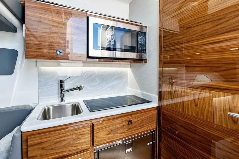  Yacht Photos Pics Luxurious 2026 Valhalla V-46 boat kitchen with wood cabinetry, sink, and microwave.
