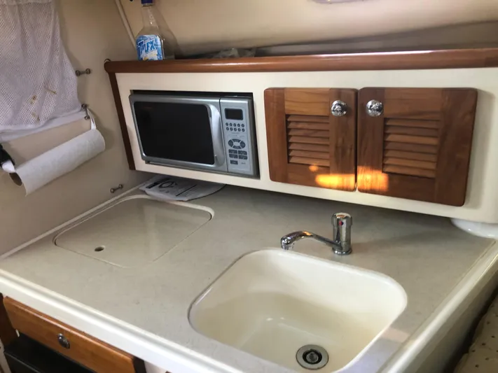 Yacht Photos Pics 2007 Pursuit 335 Offshore boat kitchen with sink, microwave, and wooden cabinets.