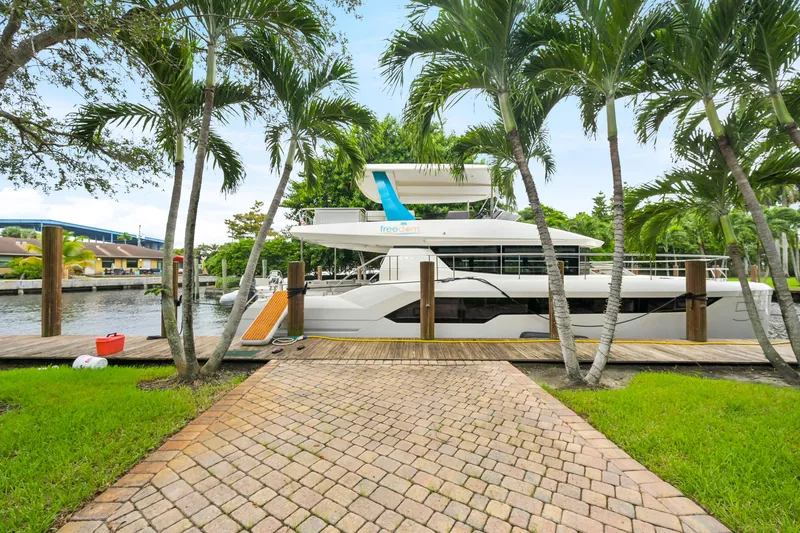 Freedom Yacht Photos Pics 2022 Leopard 53 Powercat docked by palm trees, showcasing sleek design and modern features.