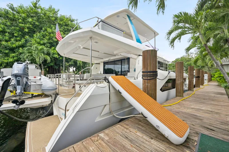 Freedom Yacht Photos Pics 2022 Leopard 53 Powercat docked, featuring spacious deck and inflatable slide, surrounded by lush greenery.