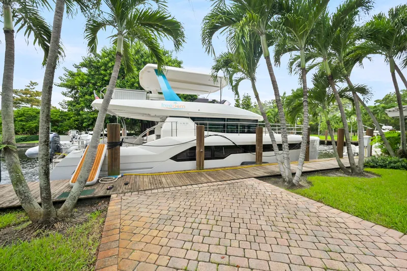 Freedom Yacht Photos Pics 2022 Leopard 53 Powercat docked among palm trees, showcasing sleek design and luxury features.