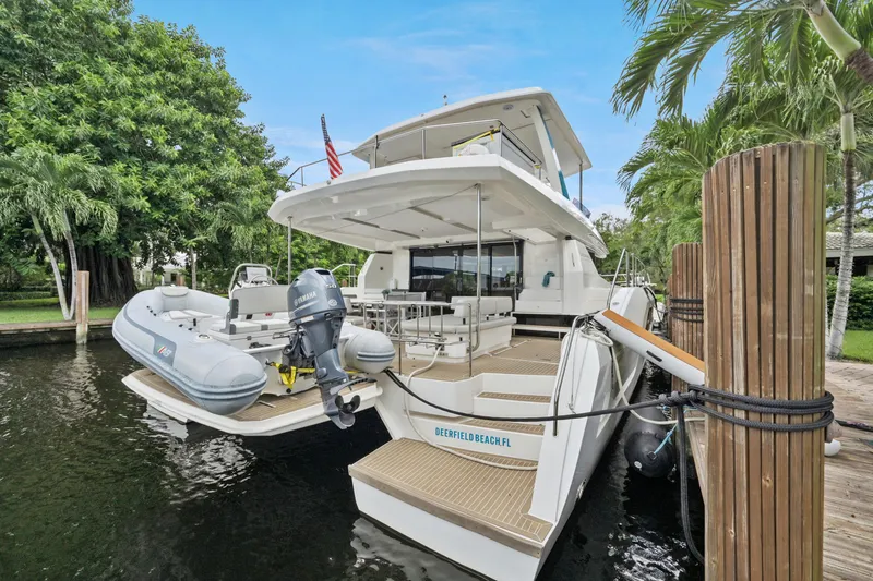 Freedom Yacht Photos Pics 2022 Leopard 53 Powercat docked with inflatable boat, surrounded by lush greenery.