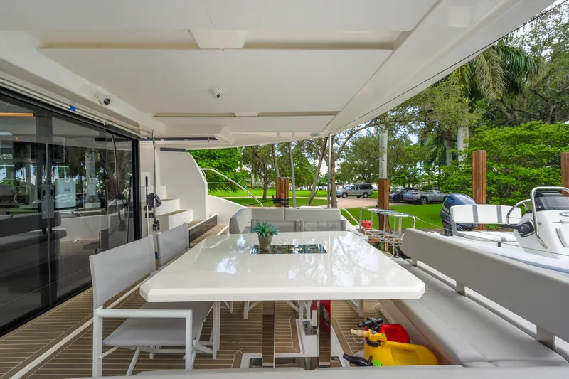 Freedom Yacht Photos Pics Leopard 53 Powercat 2022 yacht with outdoor dining area and lush greenery backdrop.
