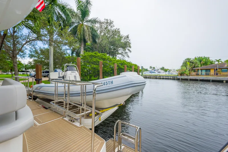Freedom Yacht Photos Pics 2022 Leopard 53 Powercat with dinghy on deck, docked by a scenic waterfront.