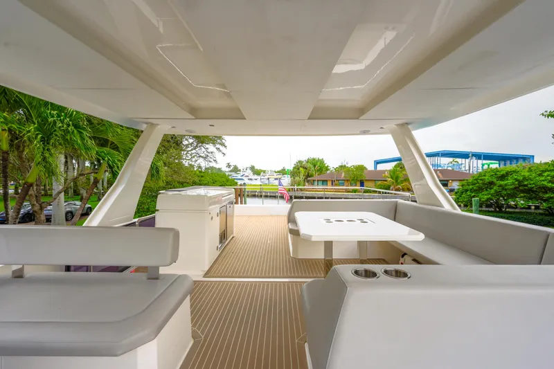 Freedom Yacht Photos Pics Luxurious 2022 Leopard 53 Powercat yacht deck with seating and table, surrounded by lush greenery.