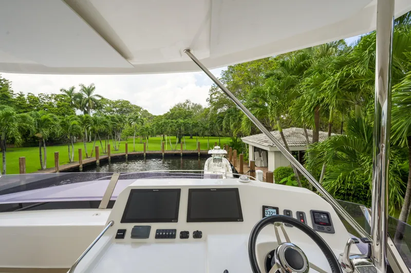 Freedom Yacht Photos Pics Helm view of 2022 Leopard 53 Powercat, surrounded by lush greenery and palm trees.