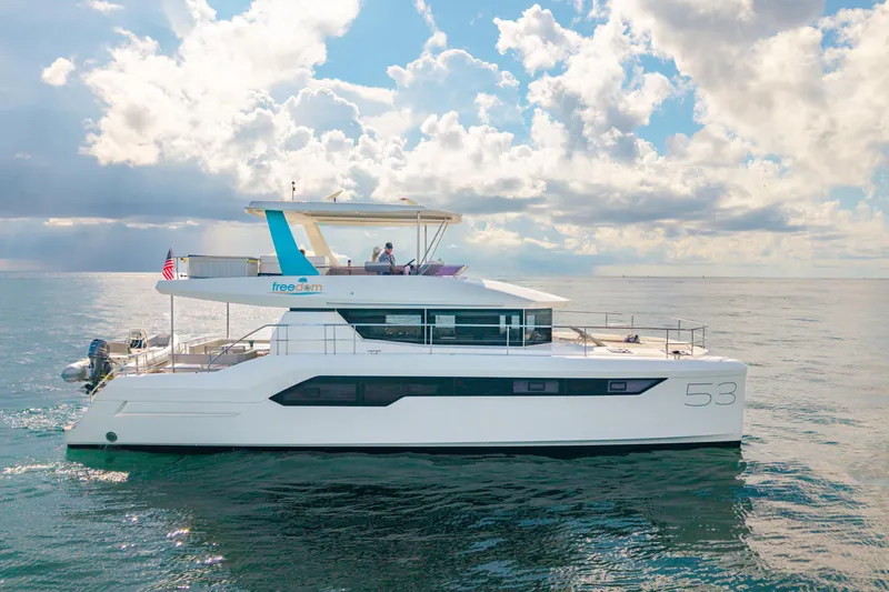 Freedom Yacht Photos Pics 2022 Leopard 53 Powercat yacht cruising on open water under a partly cloudy sky.