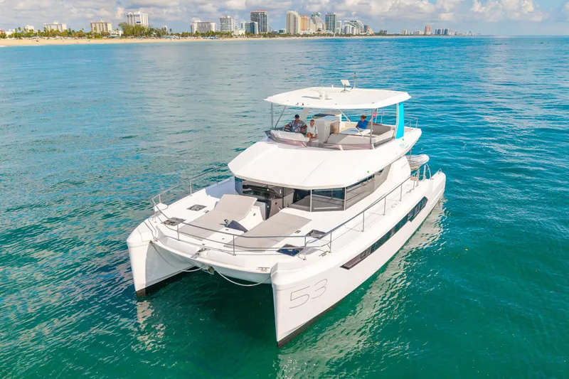 Freedom Yacht Photos Pics 2022 Leopard 53 Powercat yacht cruising on clear blue waters near a city skyline.