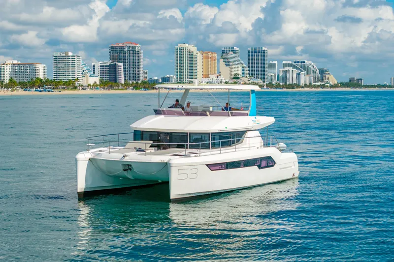 Freedom Yacht Photos Pics 2022 Leopard 53 Powercat yacht cruising near a city skyline on a sunny day.