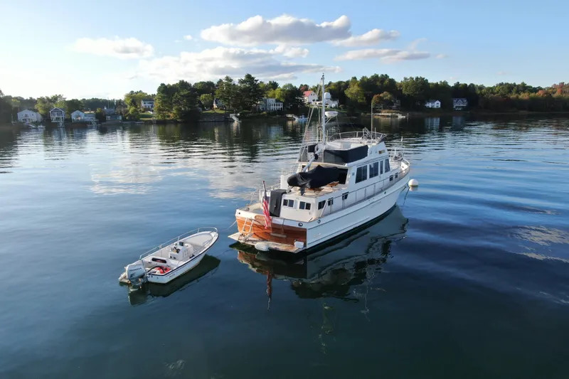 Maximon Yacht Photos Pics 1989 Grand Banks 46 yacht anchored on serene water with a small boat nearby.