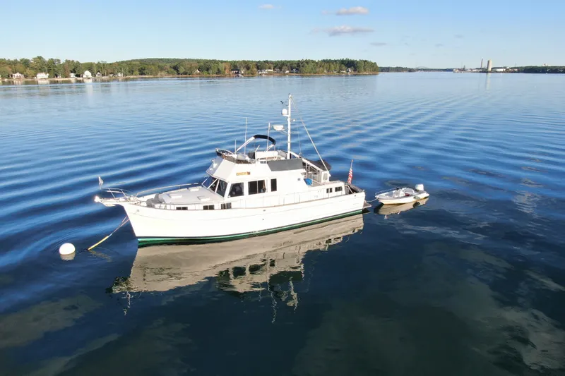 Maximon Yacht Photos Pics 1989 Grand Banks 46 yacht anchored on calm water with a small boat nearby.