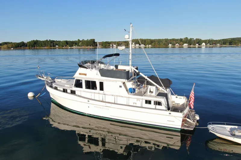 Maximon Yacht Photos Pics 1989 Grand Banks 46 yacht moored on calm water with scenic shoreline background.