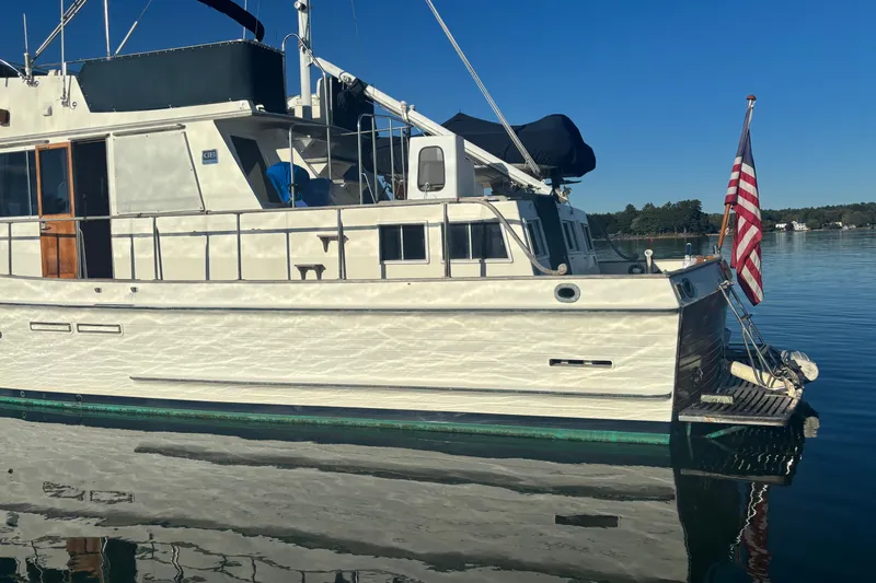 Maximon Yacht Photos Pics 1989 Grand Banks 46 yacht docked on calm water with American flag.