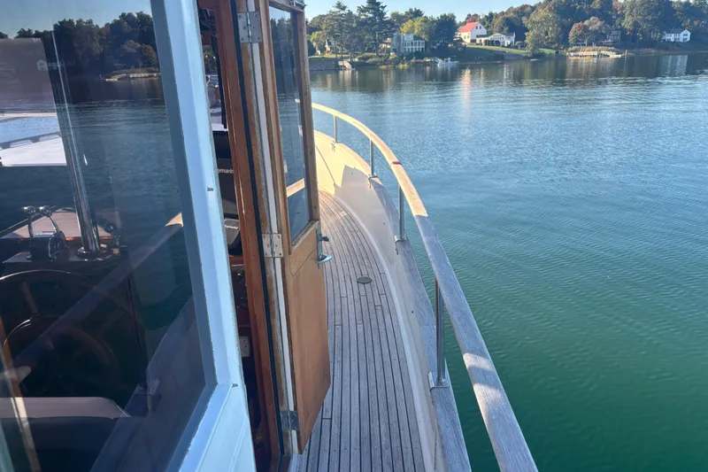Maximon Yacht Photos Pics 1989 Grand Banks 46 yacht with wooden deck, cruising on calm waters near a scenic shoreline.
