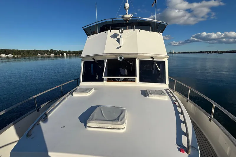 Maximon Yacht Photos Pics 1989 Grand Banks 46 yacht on calm water under a blue sky with clouds.