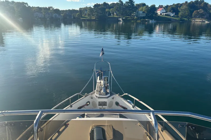 Maximon Yacht Photos Pics Bow view of 1989 Grand Banks 46 yacht on calm water, scenic shoreline in background.