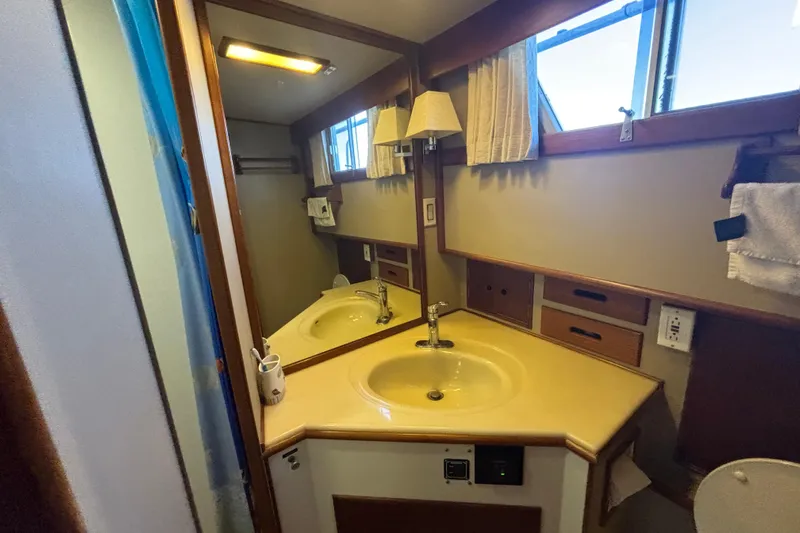 Maximon Yacht Photos Pics Bathroom interior of 1989 Grand Banks 46 yacht, featuring sink, mirror, and storage.