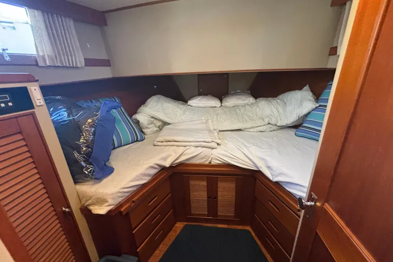 Maximon Yacht Photos Pics Cozy cabin interior of 1989 Grand Banks 46 yacht with comfortable bedding and wooden storage.