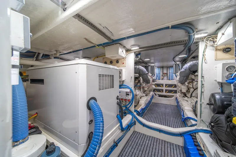 Odisea Yacht Photos Pics Engine room of 1995 Tollycraft 57 Walk Around Pilothouse with machinery and blue hoses.