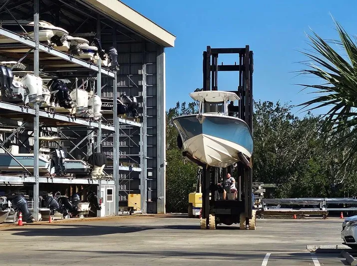  Yacht Photos Pics Forklift transporting 2012 Edgewater 318CC boat near storage facility.