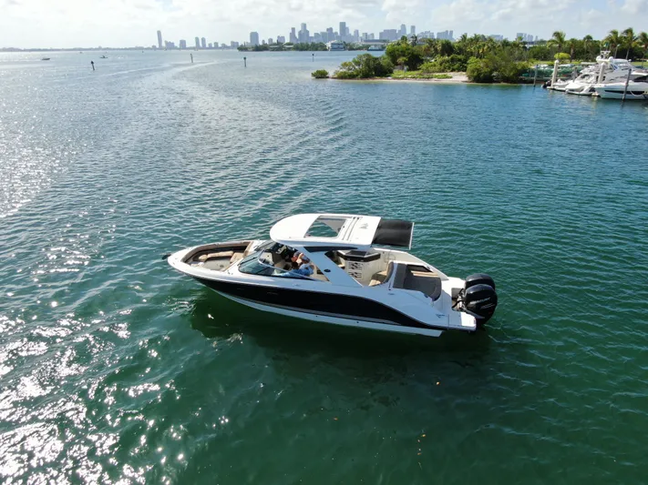  Yacht Photos Pics 2018 Sea Ray 310 SLX boat cruising on a sunny day near a city skyline.
