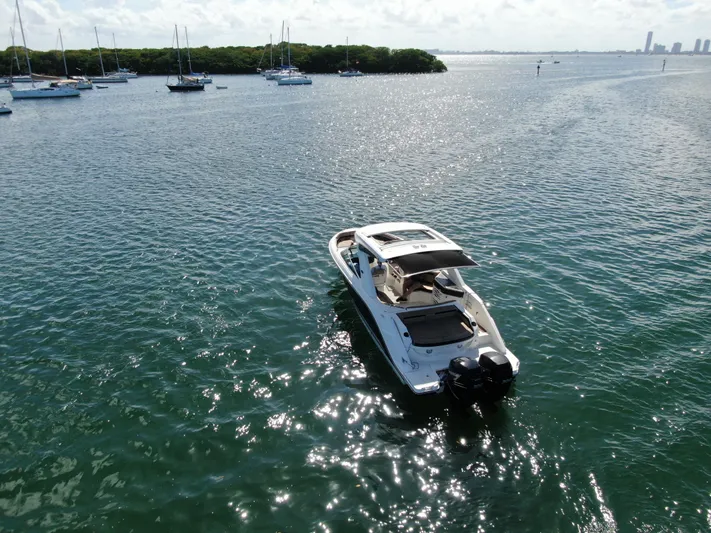  Yacht Photos Pics 2018 Sea Ray 310 SLX boat cruising on a sunny, calm sea with sailboats in the background.