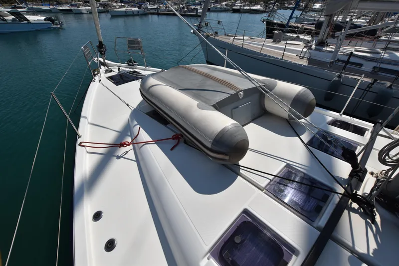 Blueconomy Yacht Photos Pics 2020 Jeanneau Sun Odyssey 490 sailboat with inflatable dinghy on deck, docked in marina.