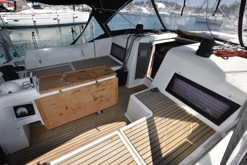 Blueconomy Yacht Photos Pics 2020 Jeanneau Sun Odyssey 490 yacht cockpit with wooden flooring and marina view.