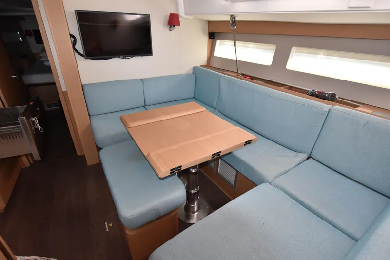 Blueconomy Yacht Photos Pics 2020 Jeanneau Sun Odyssey 490 interior with blue seating and foldable table.
