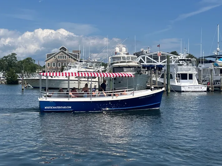 Joseph Packer Yacht Photos Pics 2024 Duffy 26 Water Taxi cruising in a marina with striped canopy and passengers.