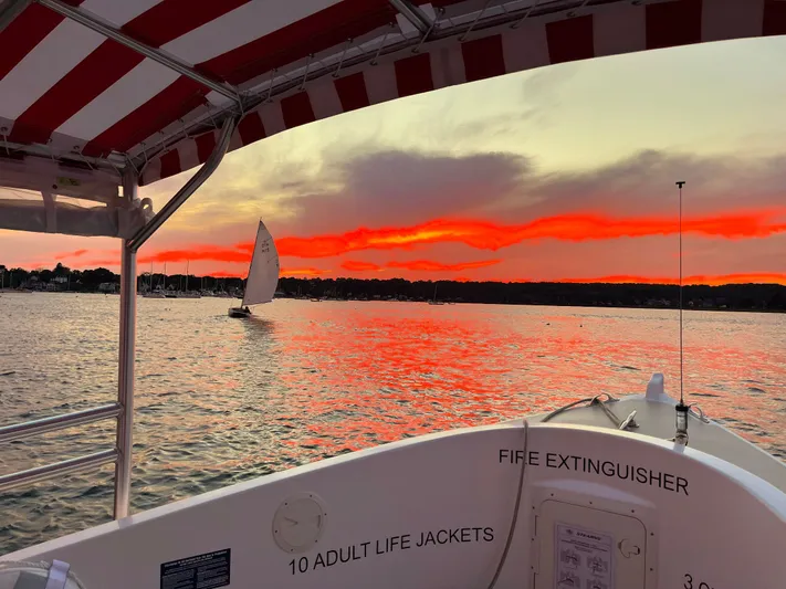 Joseph Packer Yacht Photos Pics 2024 Duffy 26 Water Taxi at sunset, vibrant sky, sailboat in distance.
