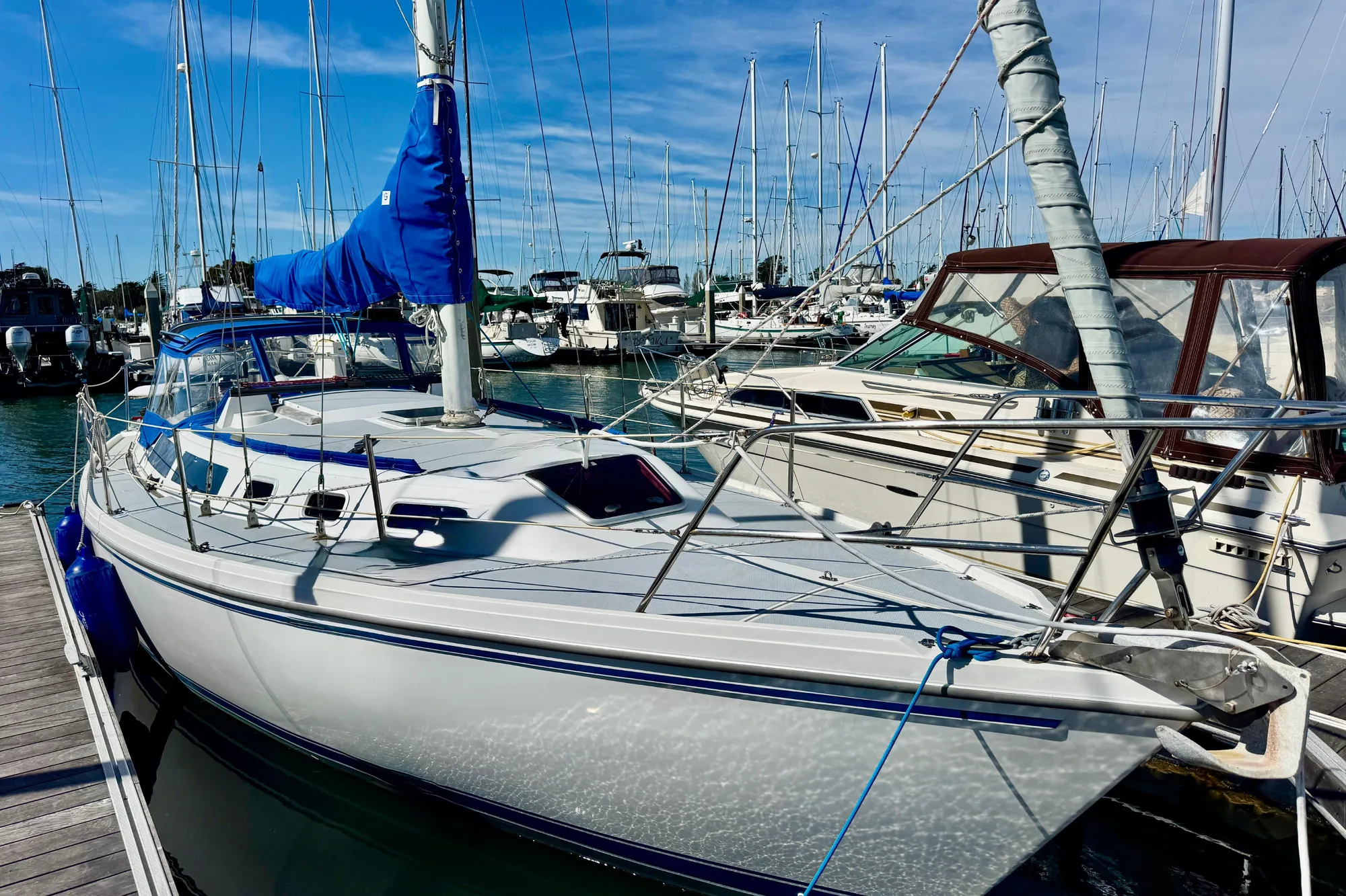 1987 Catalina 34 sailboat docked in a marina under clear blue skies.