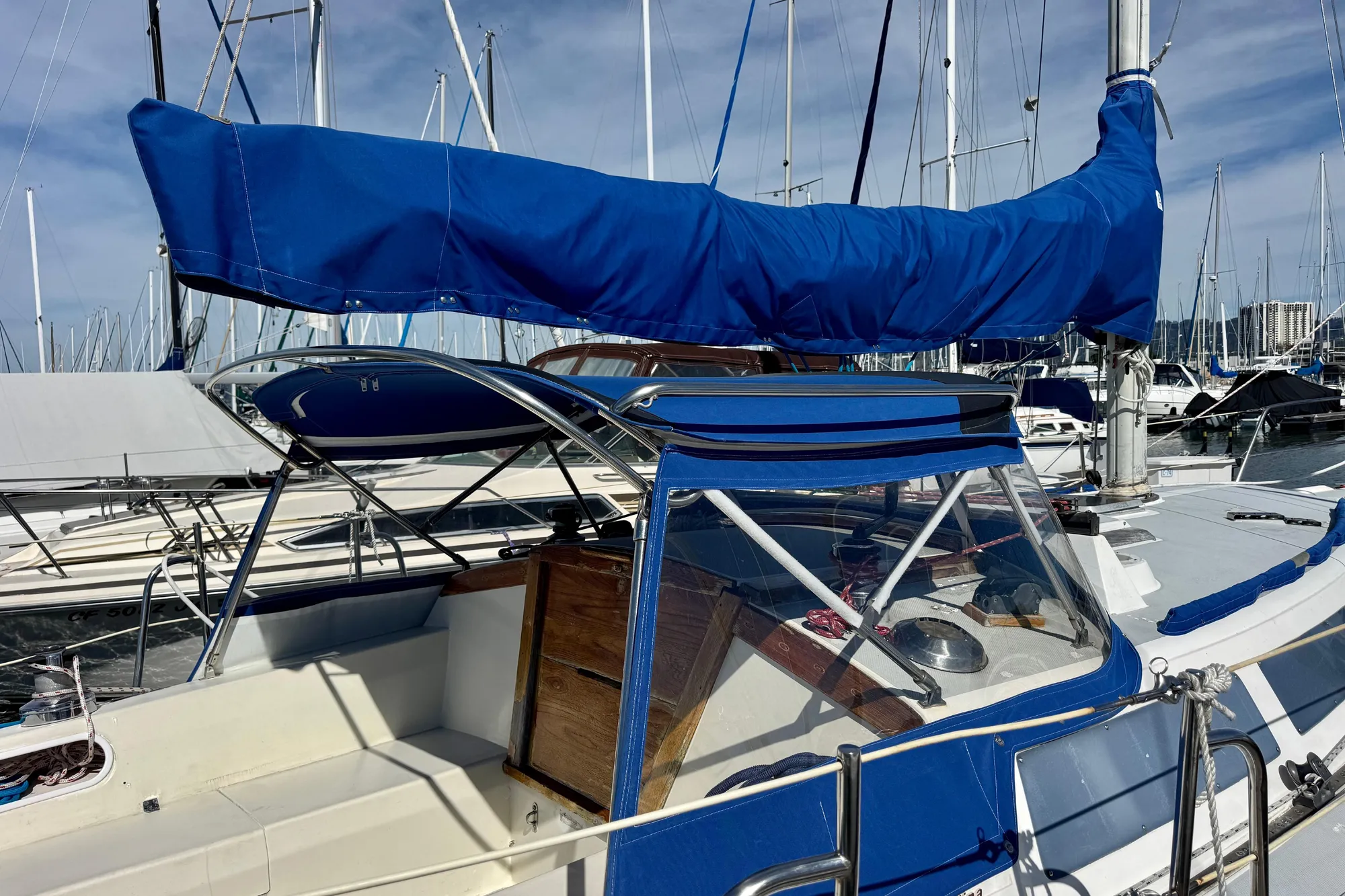 1987 Catalina 34 sailboat with blue cover docked at marina.