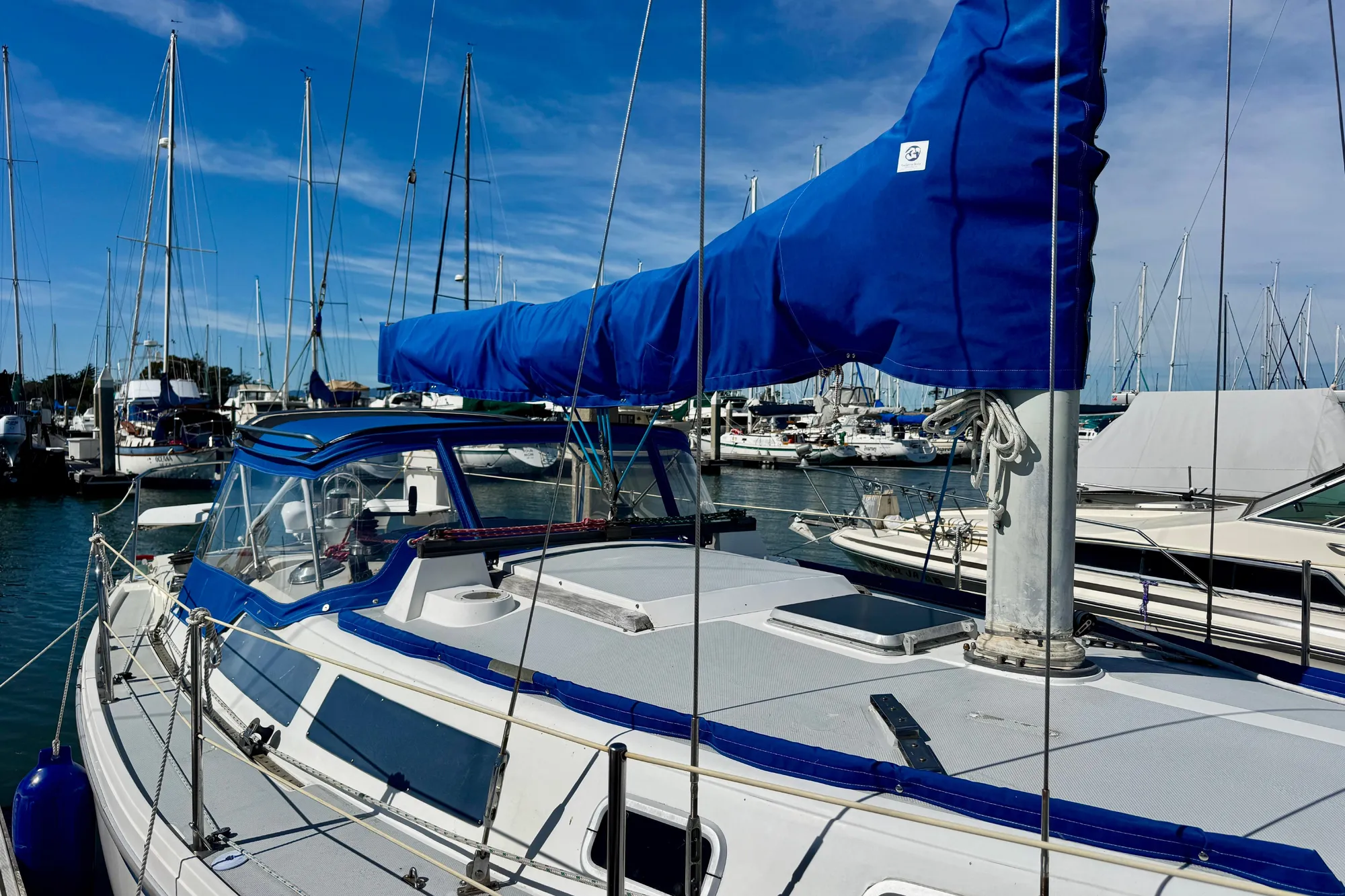 1987 Catalina 34 sailboat docked in marina, featuring blue sail cover and clear skies.