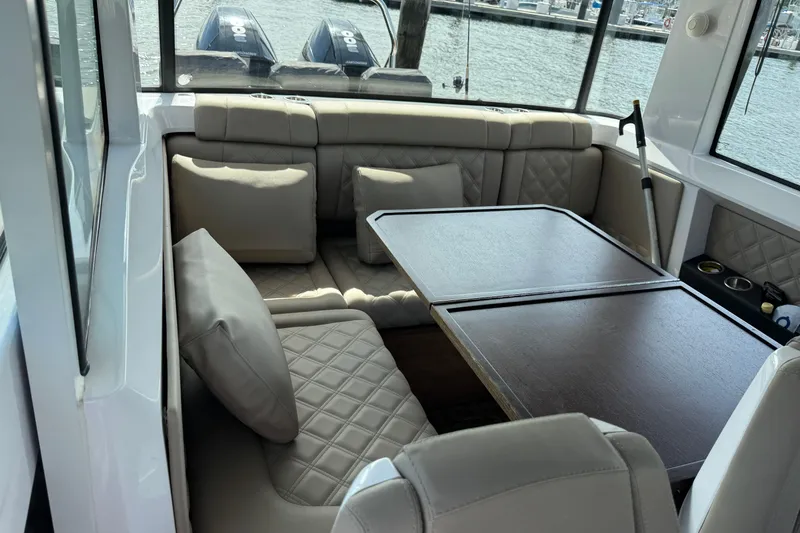  Yacht Photos Pics Luxurious seating area in 2022 Axopar 37 XC CROSS CABIN boat with elegant cushions and table.