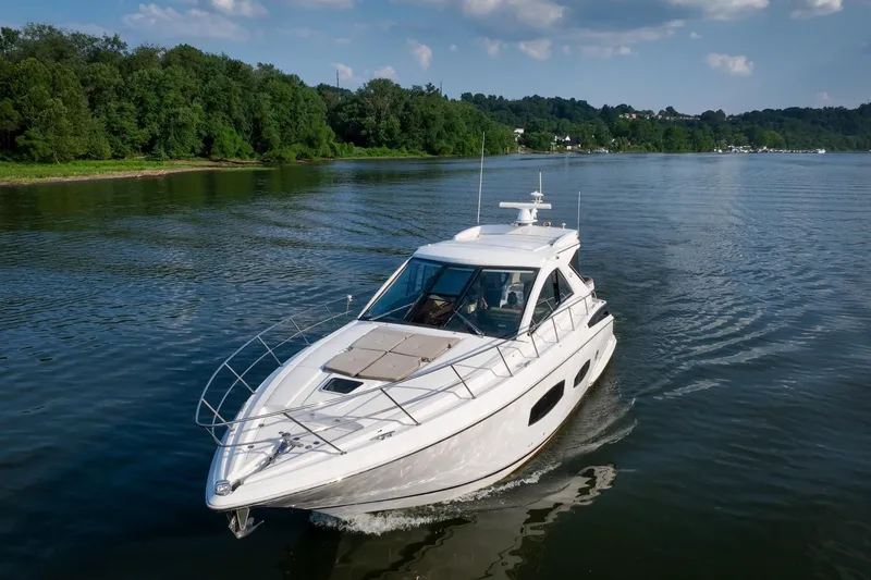  Yacht Photos Pics 2015 Regal 53 Sport Coupe cruising on a serene lake with lush green shoreline.