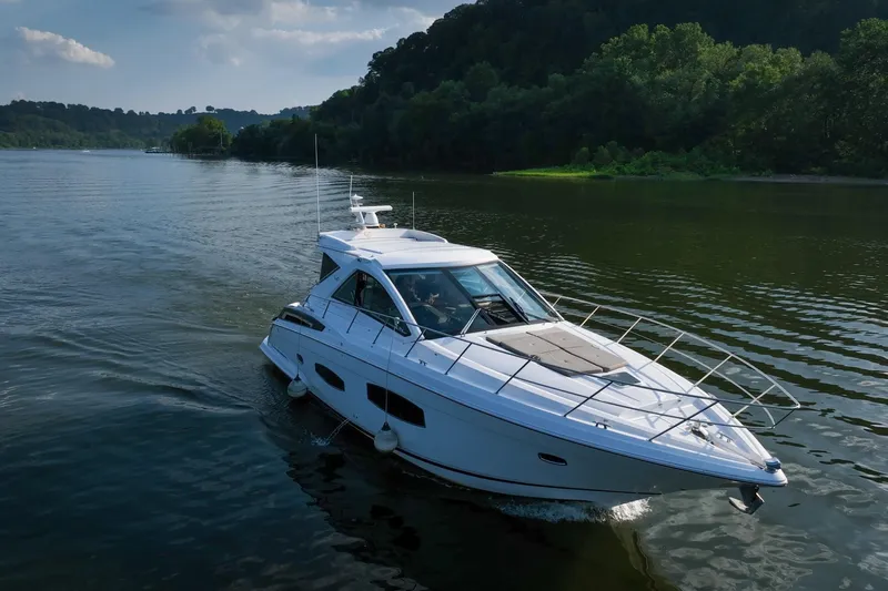  Yacht Photos Pics 2015 Regal 53 Sport Coupe cruising on a serene lake with lush green surroundings.