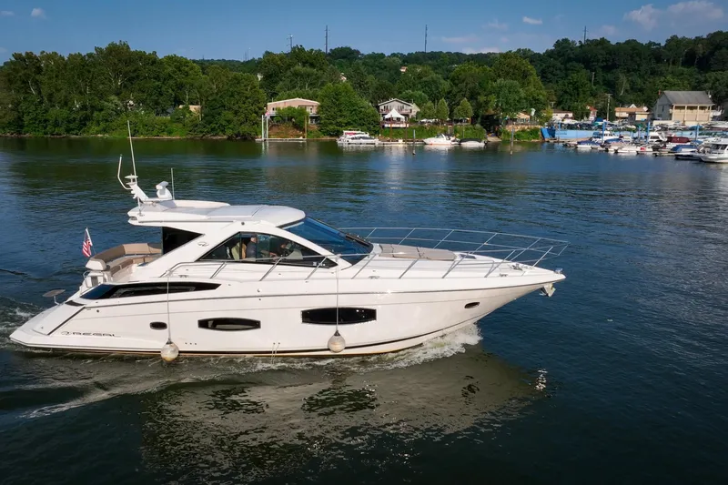  Yacht Photos Pics 2015 Regal 53 Sport Coupe yacht cruising on a scenic lake with lush greenery.