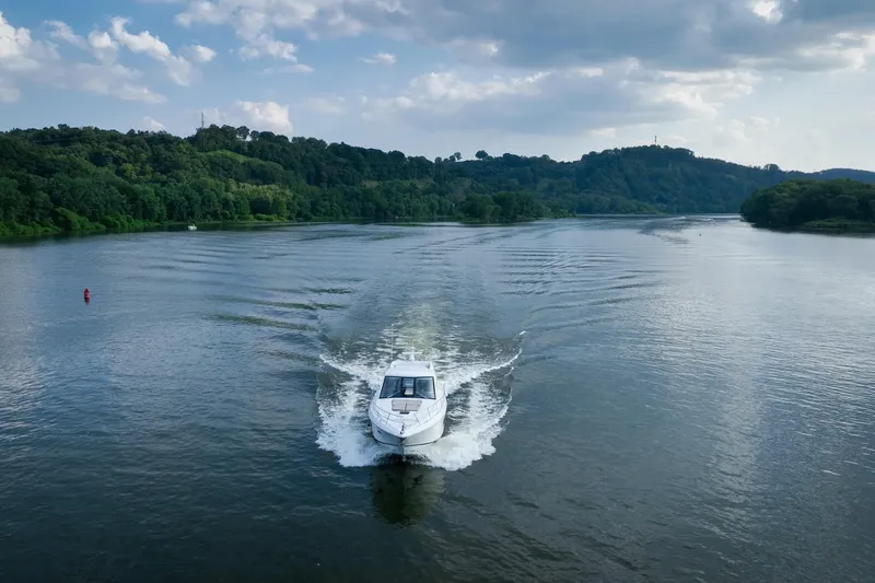  Yacht Photos Pics 2015 Regal 53 Sport Coupe cruising on a scenic river with lush green hills.