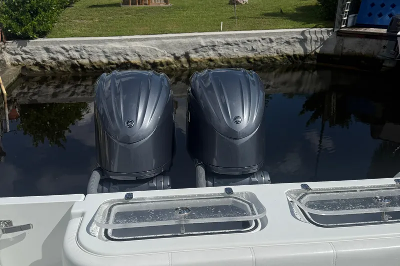  Yacht Photos Pics 2023 Contender 30 Tournament boat with dual outboard engines docked by a canal.