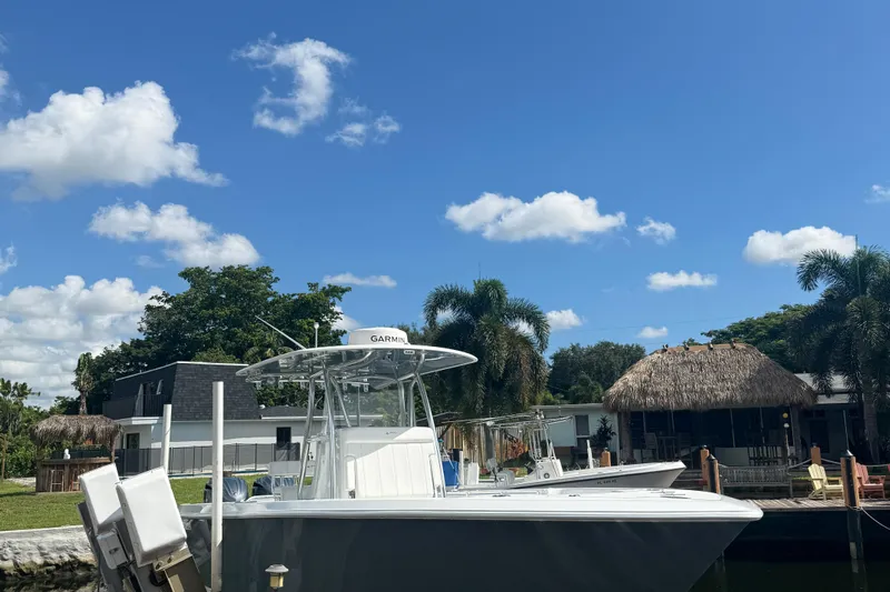  Yacht Photos Pics 2023 Contender 30 Tournament boat docked by tropical waterfront homes under blue sky.