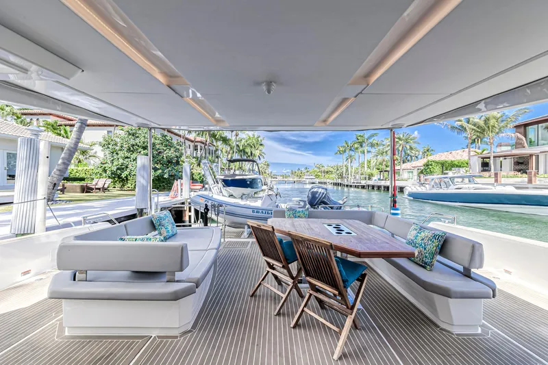Double Feature Yacht Photos Pics Outdoor seating area on a 2023 Leopard 53 Powercat yacht, docked by a scenic waterfront.
