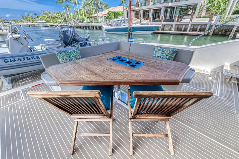 Double Feature Yacht Photos Pics Outdoor seating area on 2023 Leopard 53 Powercat yacht, featuring a wooden table and waterfront view.